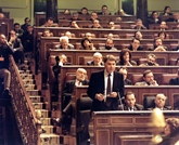 El candidato a la Presidencia Felipe González habla desde el escaño con su Grupo Parlamentario Socialista detrás. A su lado, Alfonso Guerra, Vicepresidente del Gobierno y Francisco Fernández Ordóñez, Ministro de Asuntos Exteriores. 