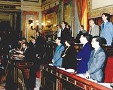 Mesa de la Cámara con sus miembros en pie, y el Secretario 4º Josep María Trías de Bes en la tribuna de oradores
